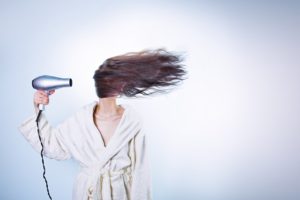 a woman with long hair blowing her hair with hairdryer